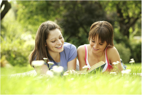 Two female friends reading on the grass